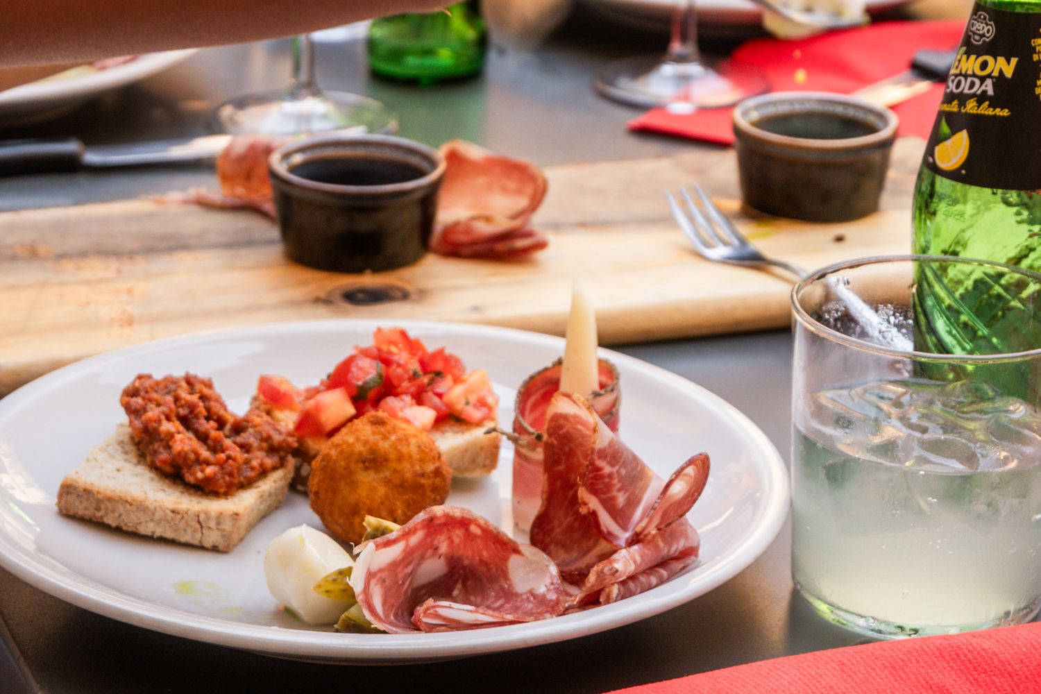 Outdoor aperitivo table in Pisa with a wooden tagliere of cured meats, bruschetta, and glasses of Aperol Spritz