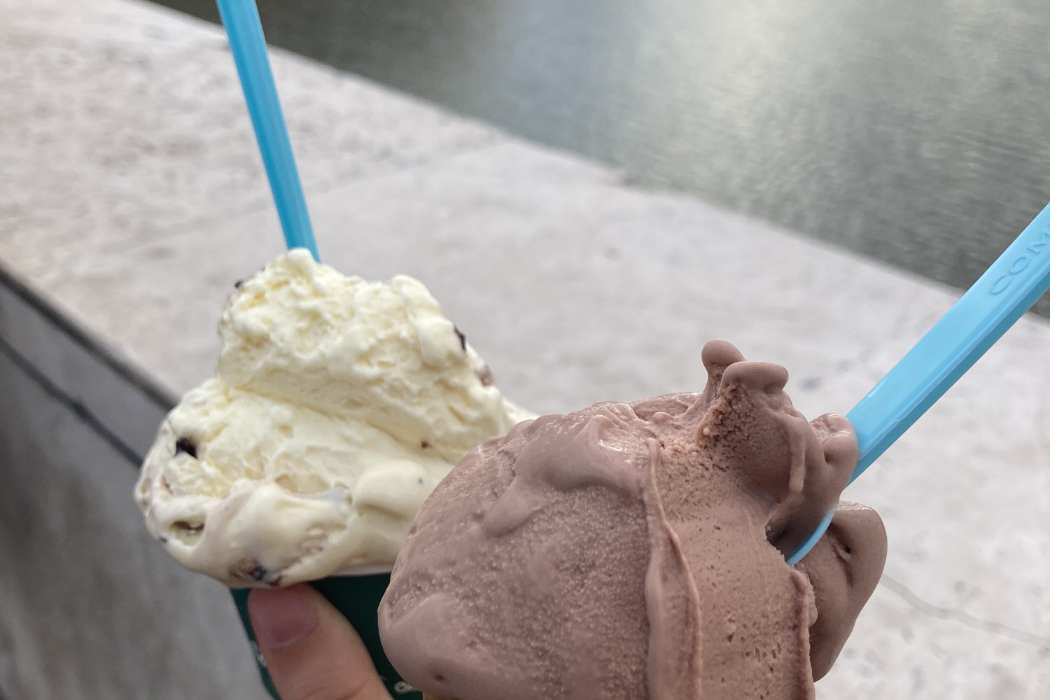 Two cups of gelato, among the top Tuscan foods in Pisa, overlooking the Arno river
