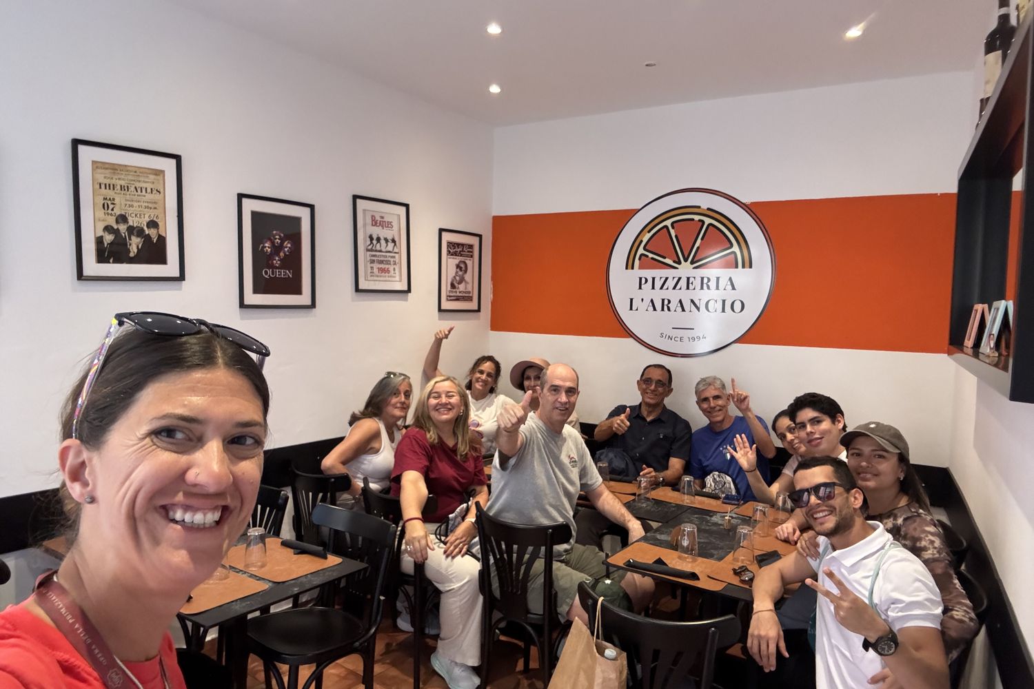 Group of tourists posing together inside Pizzeria L'Arancio in Pisa during a food tour